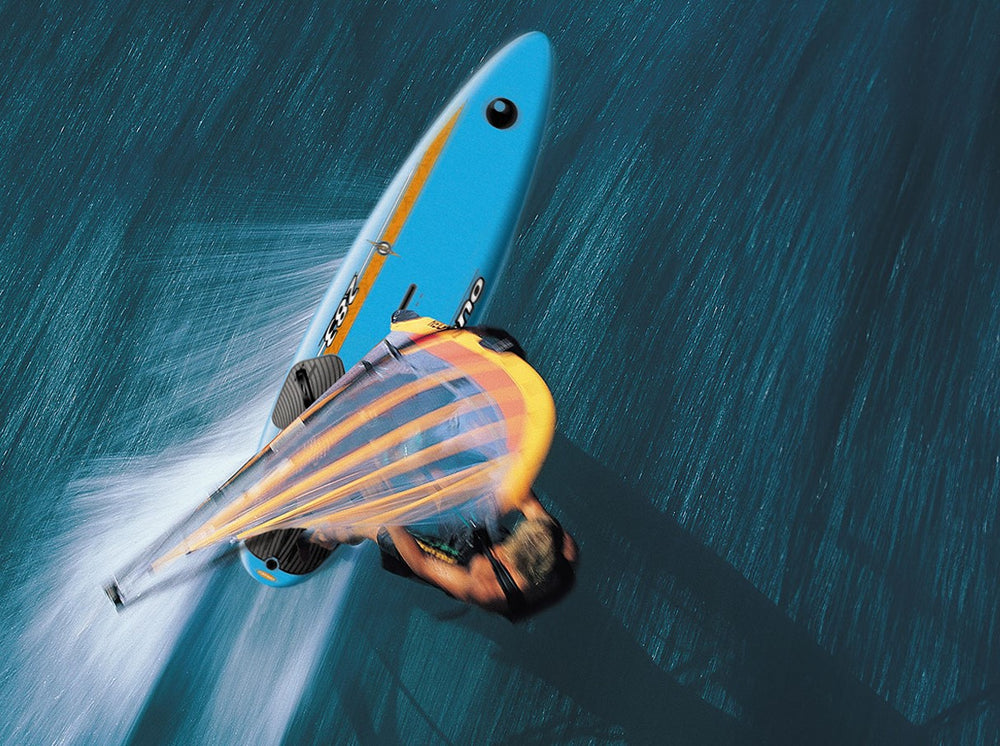 Action shot of a windsurfer catching speed on a Bic Sport board in open waters